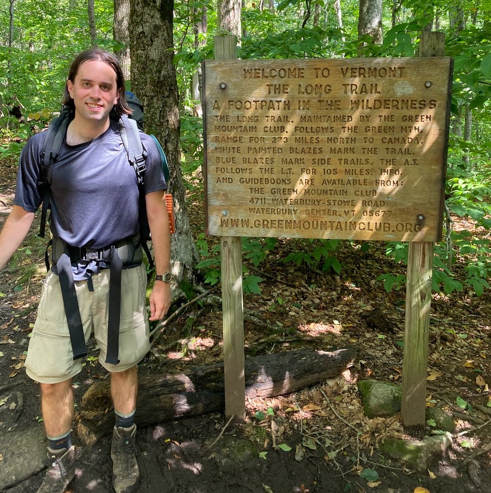 A photograph of the author standing by a sign that says 'Welcome to the Long Trail'